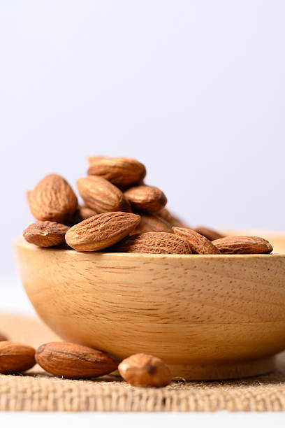 istock Raw almond nut seed in wooden bowl with white background 2221003515