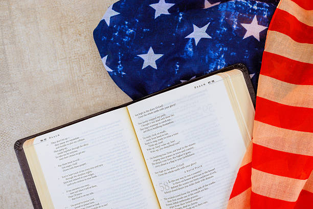 istock Open Bible book with poetry lays on table surrounded by American flag star-patterned fabric, symbolizing patriotism reflection 2221009729