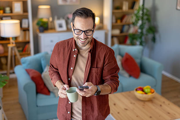 istock Man Checking Phone While Sipping Coffee in Living Room 2221010309