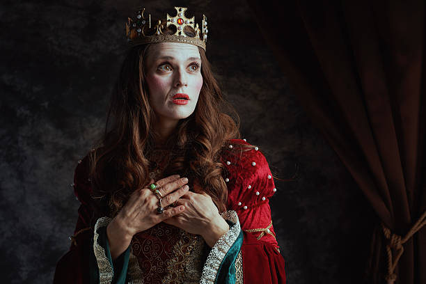 istock surprised medieval queen in red dress with white makeup 2221012019