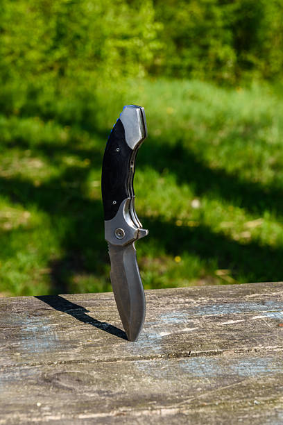 istock Folding knife stuck in the old wooden board 2221012060