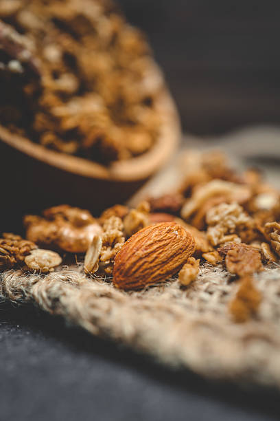 Close-up of granola and almond on a rustic textile surface. Macro view highlighting texture and detail of healthy breakfast ingredients with natural warm tones