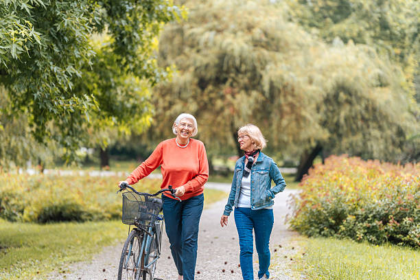 istock Senior Friends Enjoy Park Stroll with Bicycle 2221029551