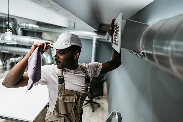 istock Maintenance worker performs air vent cleaning in modern office setting to ensure optimal air quality and comfort for employees during work hours 2221030540