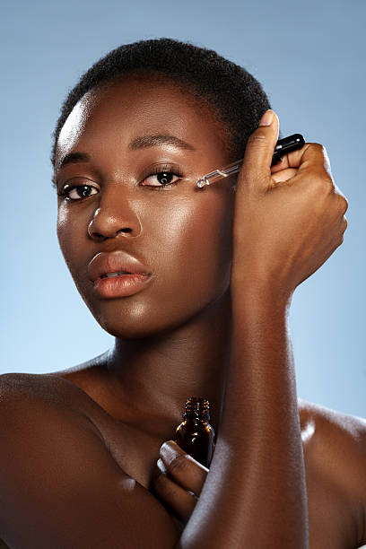 istock Skincare routine featuring a woman applying serum to her face in a bright studio setting 2221030551