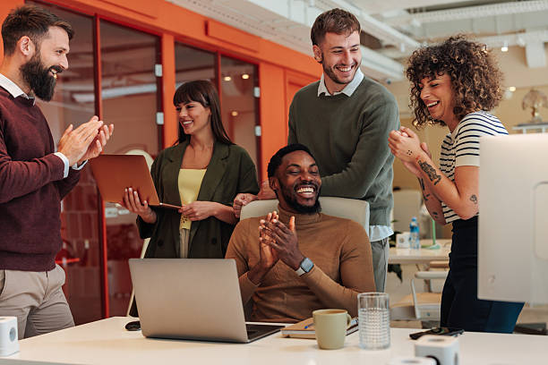 Diverse business team clapping hands, celebrating success in modern office