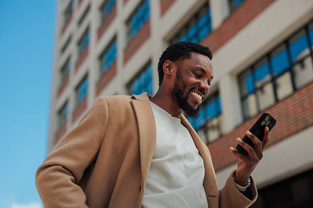 istock Young businessman smiling while using mobile phone in the city 2221031668