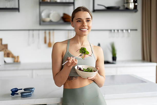 istock Sportswoman eating fresh salad in kitchen after workout 2221033919