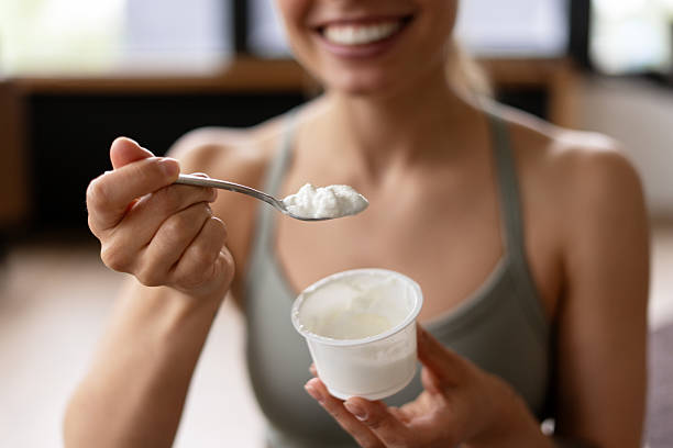 istock Smiling sportswoman eating yogurt with a spoon after workout selective focus 2221033929