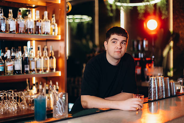 istock Man Relaxing at a Bar Counter with Various Bottles in the Background 2221038955
