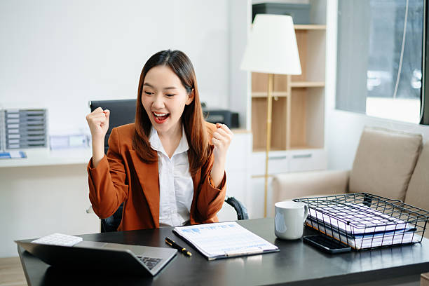 istock Asian female office worker business suits smiling at camera with working notepad, tablet and laptop documents in office 2221039412