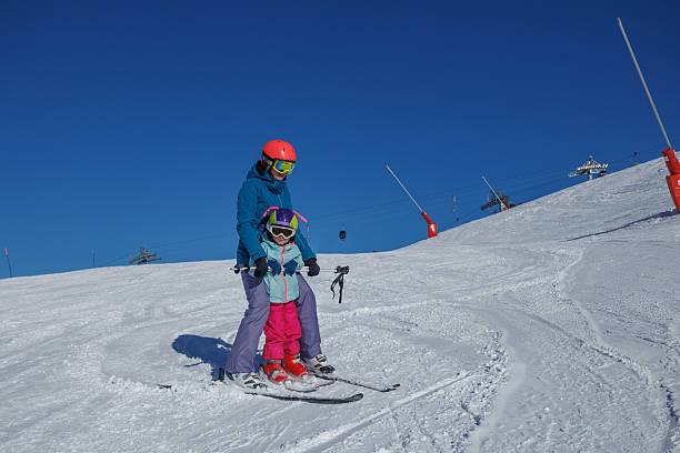 istock Instructor and kid girl on flat slope train to make ski turns 2221039872