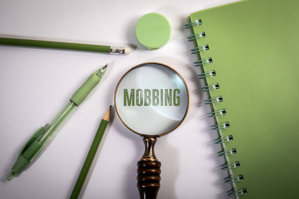 istock Mobbing. Text Under Magnifying Glass with Green Stationery on White Background 2221041828