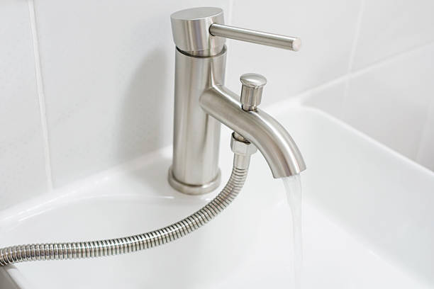 istock Water flows from a tap into a sink on a gray background close-up. 2221042462