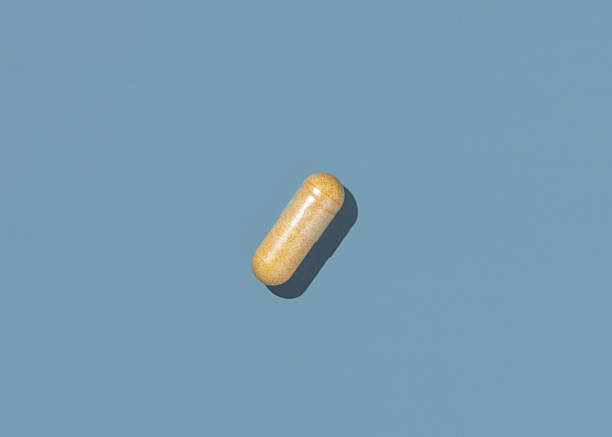 istock Beige Medical capsule on blue top view, hard shadows. Taking dietary supplements 2221042770