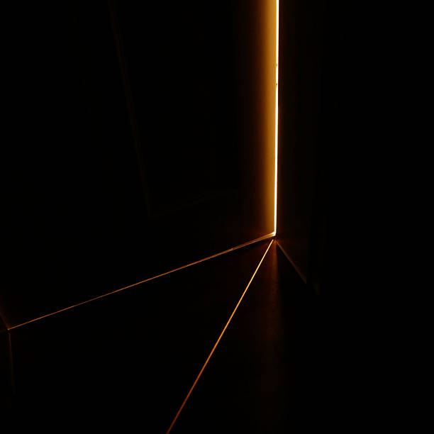Light shining in almost complete darkness through a thin slit of a door between two rooms