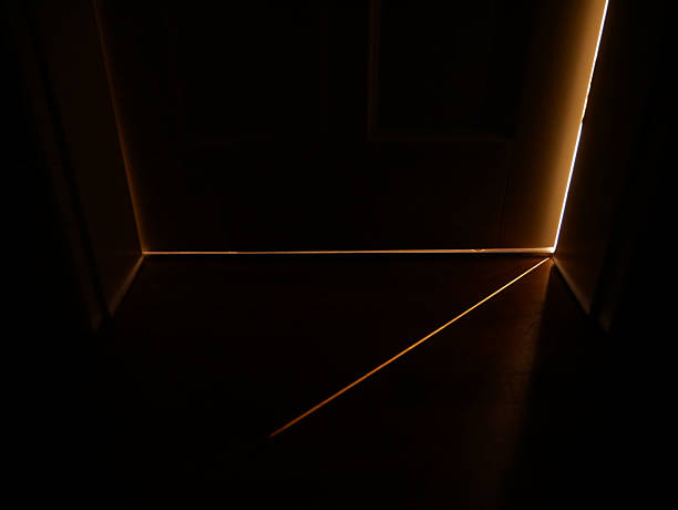 istock Light shining in almost complete darkness through a thin slit of a door between two rooms 2221049152