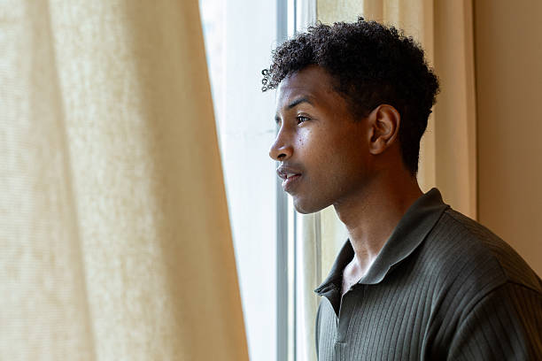 istock Young man looking out the window with a pensive expression 2221051838