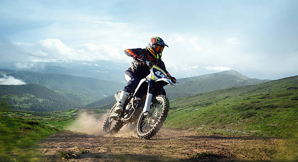 istock Professional biker in helmet speeds on mountain trail with dust and panoramic background of green hills. Composite image 2221053818
