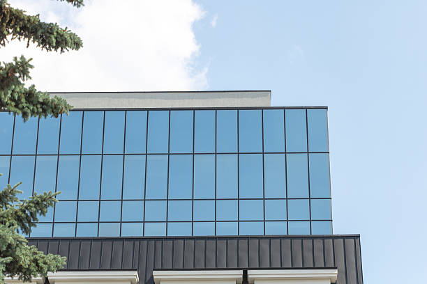 istock A modern building with large windows reflecting the clear blue sky, with trees in front of it 2221054185