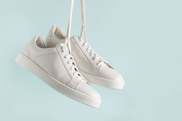 istock New white sneakers hanging against light blue background. 2221054253