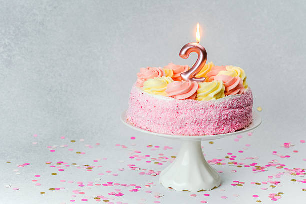 istock Celebrating a second birthday with a pink cake and confetti on the table 2221055095