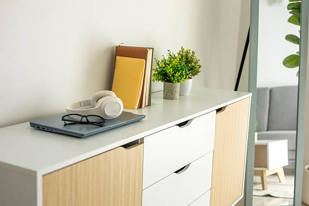 A simple living room showcasing a sideboard cabinet, ceramic tile flooring, and a white wall background.