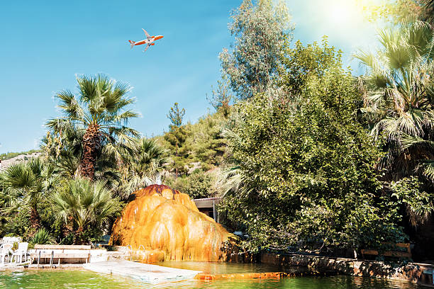Passenger plane flies over orange travertine with mineral water with iron oxide.