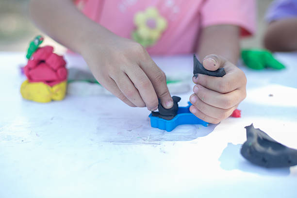 istock A young girl is playing with clay on a table. 2221056228