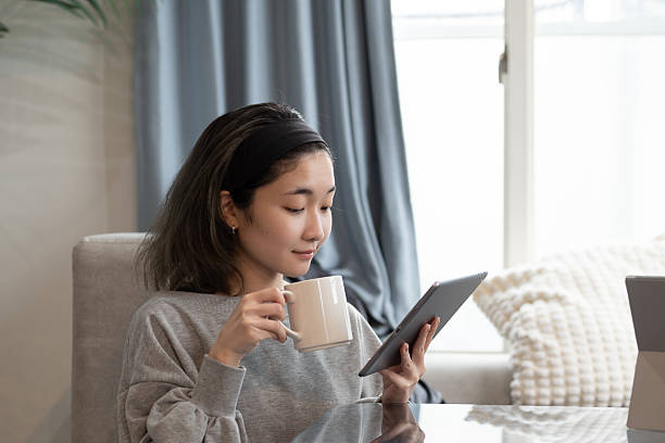 istock A young Japanese woman drinking coffee while watching the news on her tablet PC 2221057286