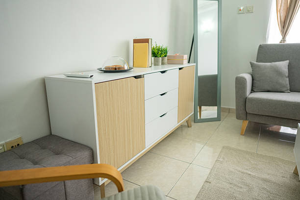 Simple-style living room featuring an armchair, grey sofa, coffee table, and living room cabinet, set against ceramic-tiled flooring and a white wall background.