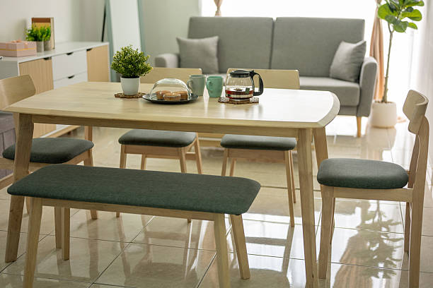 Scandinavian-style living room featuring a dining table set, gray sofa, coffee table, and a living room cabinet, set against ceramic-tiled flooring and a white wall background.