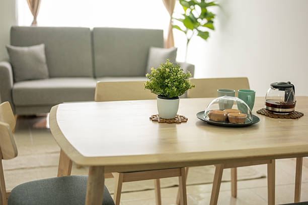 Elegant table setting with white flowers in glass vases, a vintage lantern snow globe, and minimalistic decor in cozy interior.