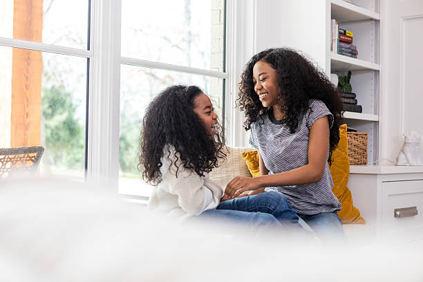 Joyful Sisterly Bonding: Laughter and Connection Near Window