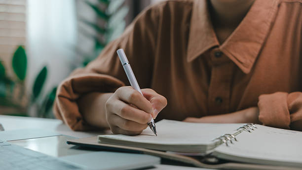 istock Close-up hand writing in notebook with pen on desk, concept of planning, journaling, learning, or working. Ideal for education, productivity, and personal development themes in modern lifestyle. 2221063593