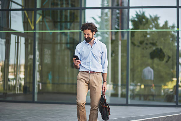 istock Businessman walking and using smartphone in front of office building 2221075834