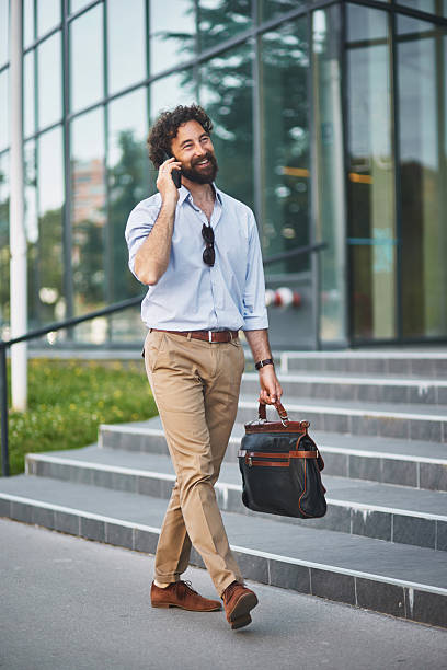 istock Businessman walking and talking on phone outside office 2221076612