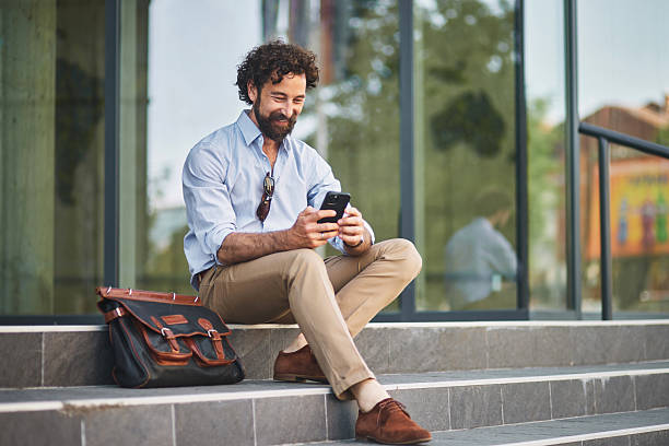 istock Businessman sitting on steps and using smartphone 2221077095