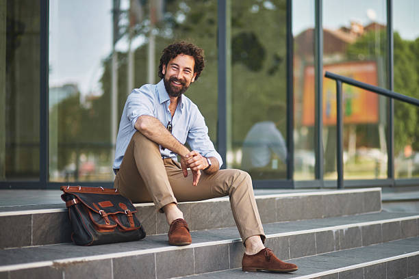 istock Smiling businessman sitting on steps outside office building 2221077220