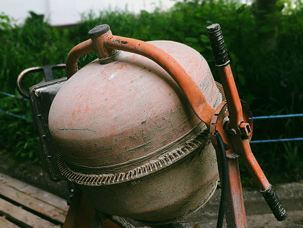 Horizontal photo of a worn orange concrete mixer at a building site. Captures a gritty, industrial mood — ideal for real-world construction content.