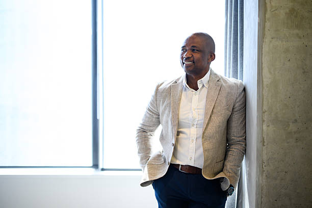 istock Front view of pensive businessman looking away while leaning against wall in bright modern hotel room, hands in pockets 2221083053