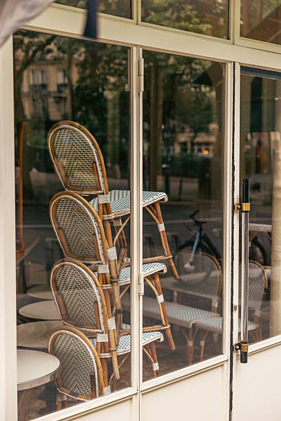 istock Stacked Rattan Bistro Chairs Seen Through Quiet Cafe Window Reflection 2221086293