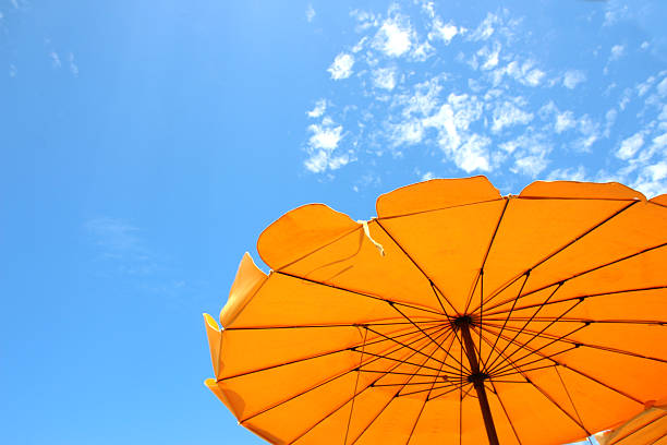 istock Yellow beach umbrella on blue sky and white clouds 2221090944