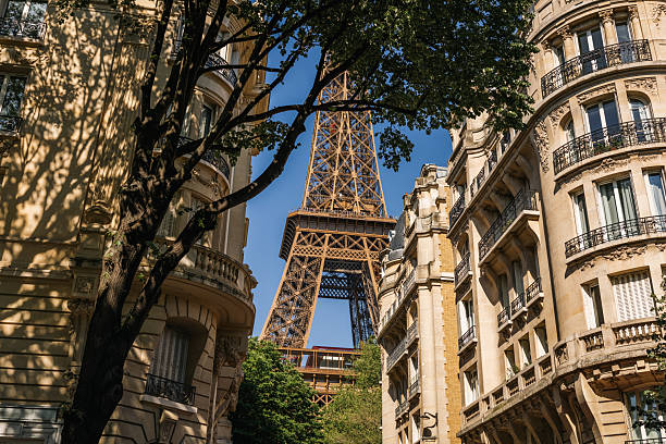 istock Eiffel Tower Peeking Between Classic Parisian Buildings on a Sunny Street 2221092240