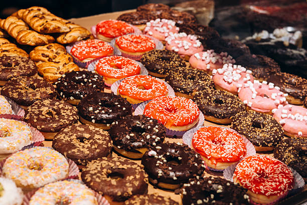 istock Colorful and appetizing glazed donuts displayed in a bakery shop window. 2221094108