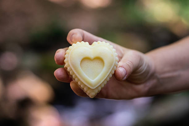 Handmade soap bar in hand outdoors, hand holding heart shaped soap bar over mountain spring