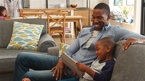 istock Father And Son At Home Sitting On Sofa In Lounge Using Digital Tablet 2221095483