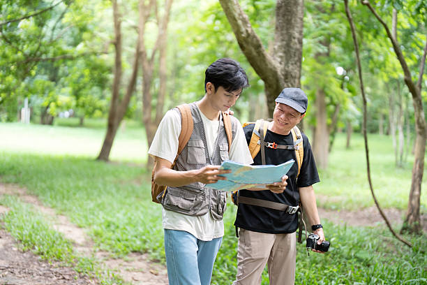 A father and son collaborate to read a map during their hike, emphasizing teamwork and the joy of exploring the great outdoors.