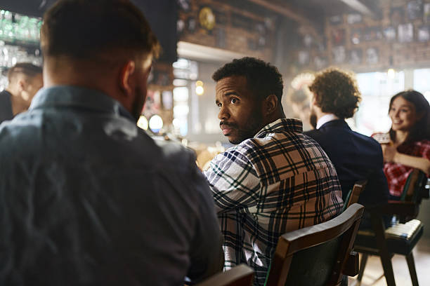 African American man communicating with his friend while sitting at bar counter.