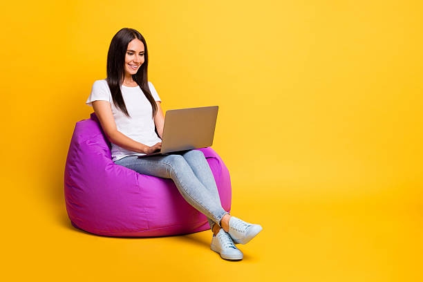 istock Full length body size photo pretty brunette working with computer programming in violet beanbag isolated on vibrant yellow color background 2221103986